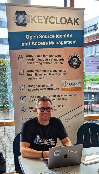 Keycloak stand at FrOSCon with Niko in front of it and our signage in the background